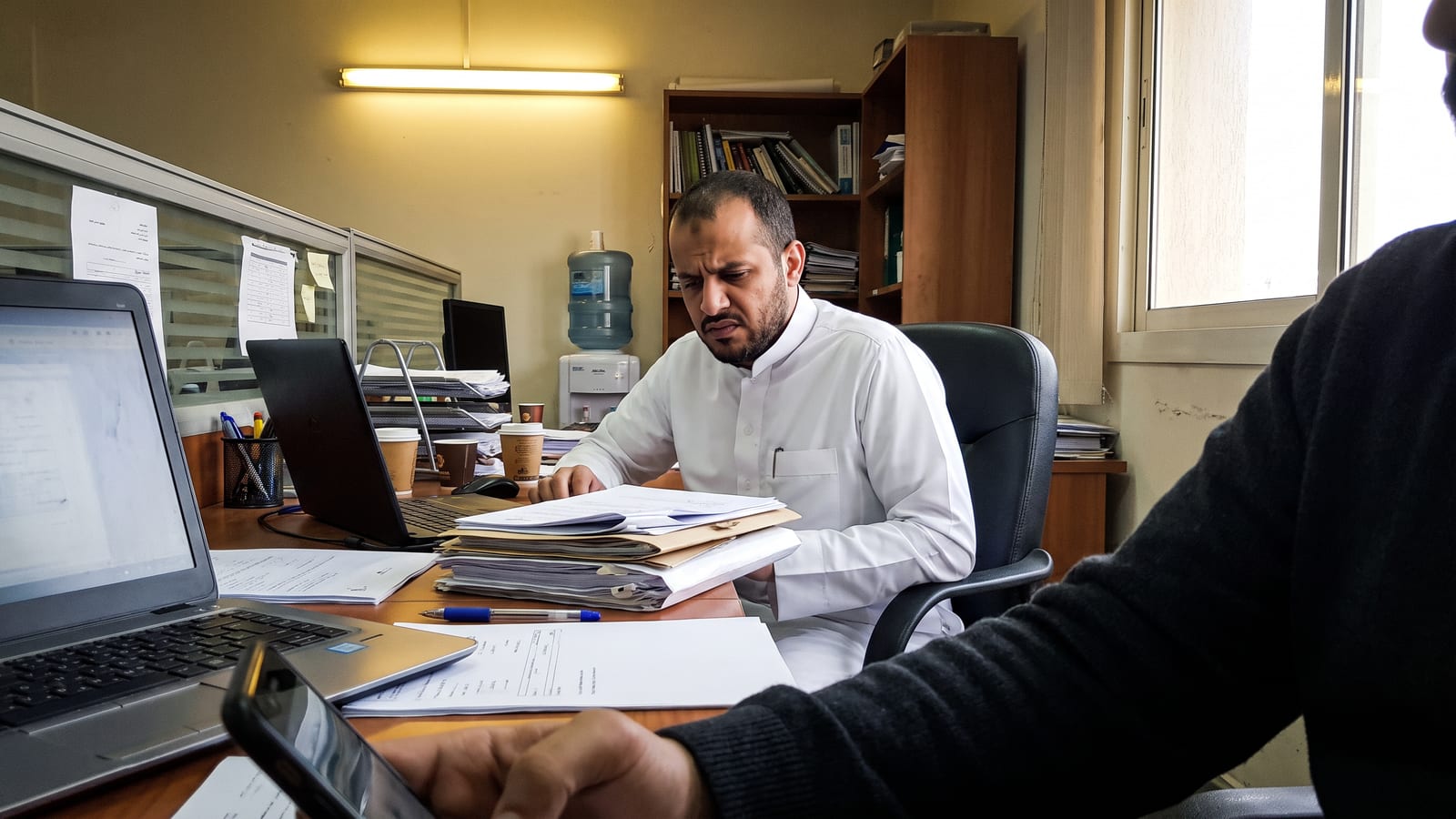 A business owner in Riyadh reviews a pile of AI agency proposals at his desk, weighing which Saudi AI agency to trust.